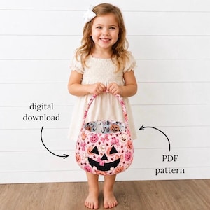 May include: A child wearing a white dress with a white hair bow holds a pink fabric bucket featuring a jack-o'-lantern face and a pattern of ghosts, pumpkins, and stars. The text digital download and PDF pattern appear on the sides of the bucket.