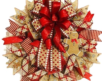 May include: A festive Christmas wreath with a large red bow as the focal point. The wreath features ribbons in various patterns, including red polka dots, stripes, and gingerbread man designs. The color palette includes red, beige, and white.