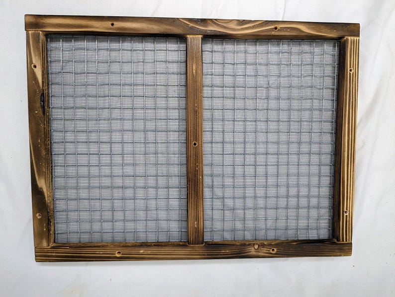 May include: A rustic wooden frame with a wire mesh insert. The frame is stained a dark brown color and has a distressed look. The mesh is a silver color and is visible through the frame.