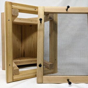 Puede incluir: Una casita de p&aacute;jaros de madera con un panel frontal extra&iacute;ble y una malla de alambre. La casita de p&aacute;jaros tiene una peque&ntilde;a plataforma de aterrizaje y un techo triangular.