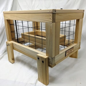 May include: A wooden raised garden bed with a wire mesh enclosure. The bed is made of natural wood and has a small wooden sign that reads "Rustic Wood Shop, Denver, MI".