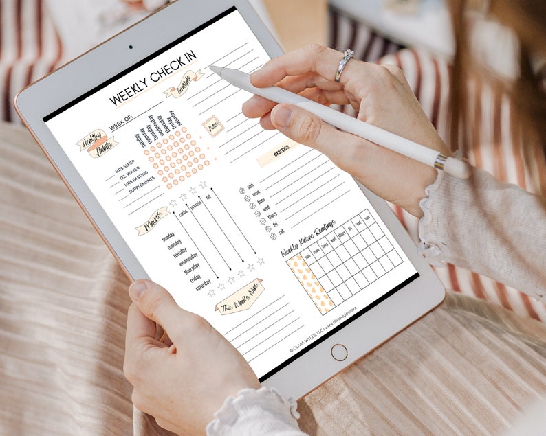 May include: A weekly check-in planner on a tablet with sections for tracking healthy habits, meals, exercise, and ketone readings. The planner includes a grid for tracking daily habits, a meal tracker with columns for carbs, protein, and fat, and a section for recording exercise.