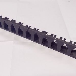 Könnte beinhalten: Schwarzer Kabelmanagement-Rack aus Kunststoff mit 15 Steckplätzen zur Organisation von Kabeln.