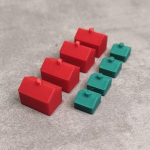 Op de afbeelding: Een set rode en groene huizen, waarschijnlijk gebruikt als spelstukken. De huizen zijn gerangschikt in een rij van groot naar klein.