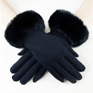 May include: A pair of black gloves with a faux fur cuff. The gloves are made of a smooth, dark fabric and feature a soft, fluffy black fur trim around the wrist area. The gloves are designed for cold weather.