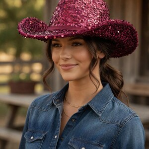May include: A burgundy sequined cowboy hat with a wide brim. The hat has a matching burgundy band and is worn with a denim shirt. The hat's sequins shimmer, catching the light. The hat is a stylish accessory.