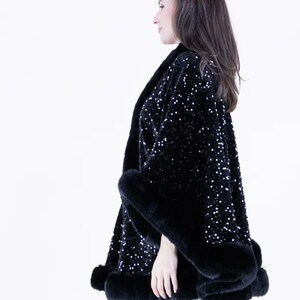 May include: A black sequined cape with a faux fur trim. The cape is open in the front and has a loose fit.