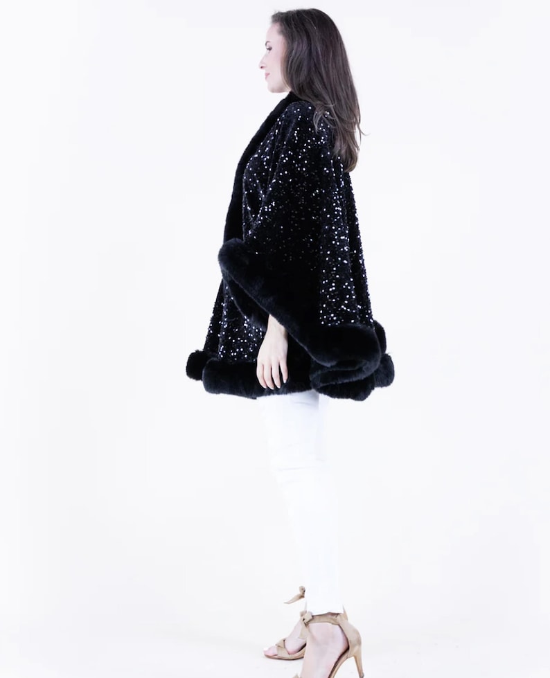 May include: A black sequined cape with a fur trim. The cape is worn by a person standing on a white background.
