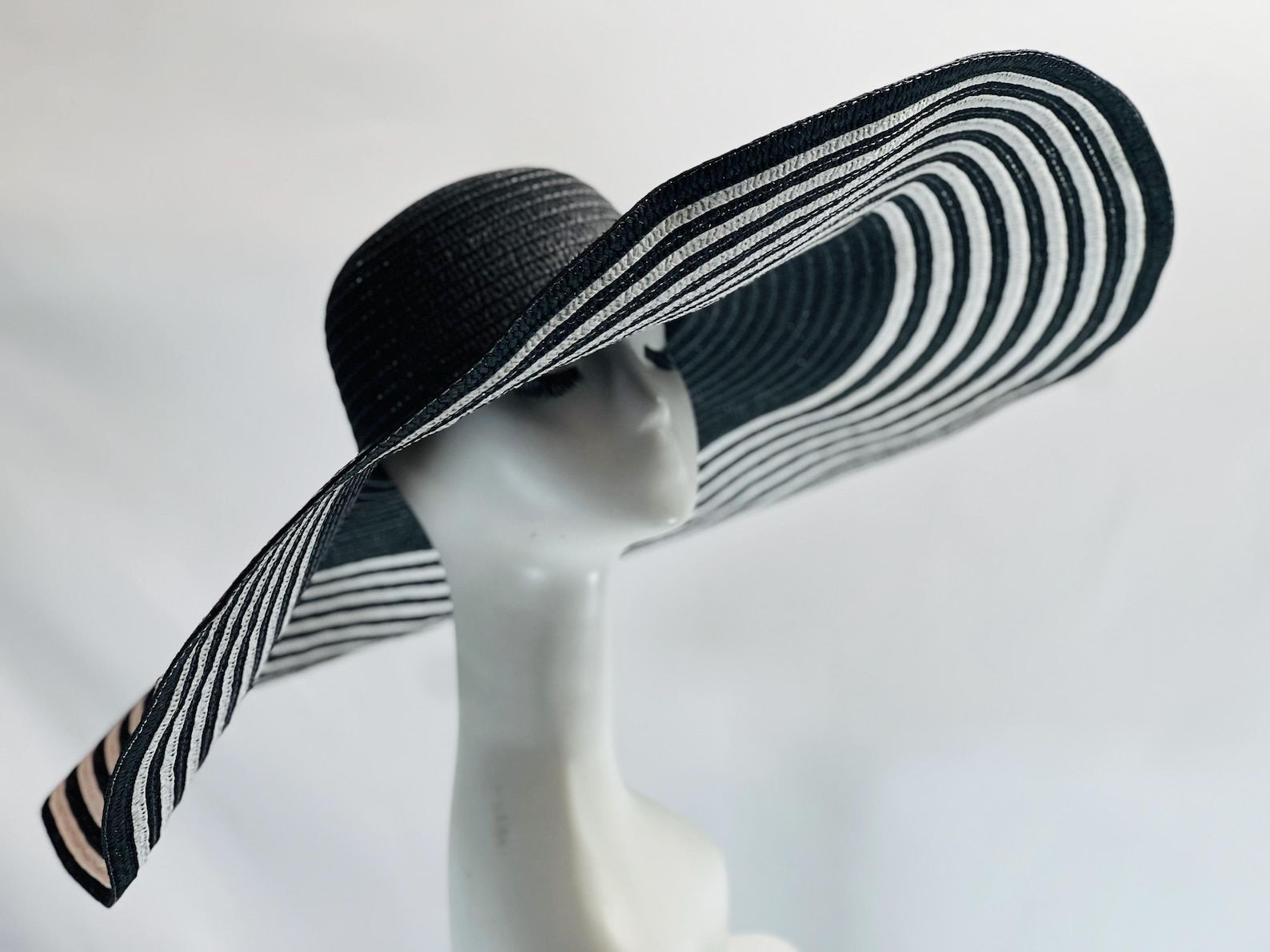Dramatic wide-brim striped hat on mannequin, perfect for summer goth sun protection or stylish beach fashion looks.