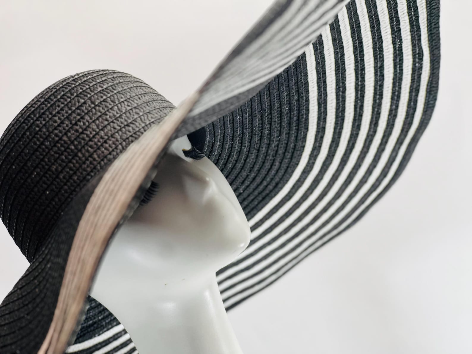 Close-up of black and white striped sun hat on mannequin, ideal for summer goth fashion and dramatic beachwear flair.