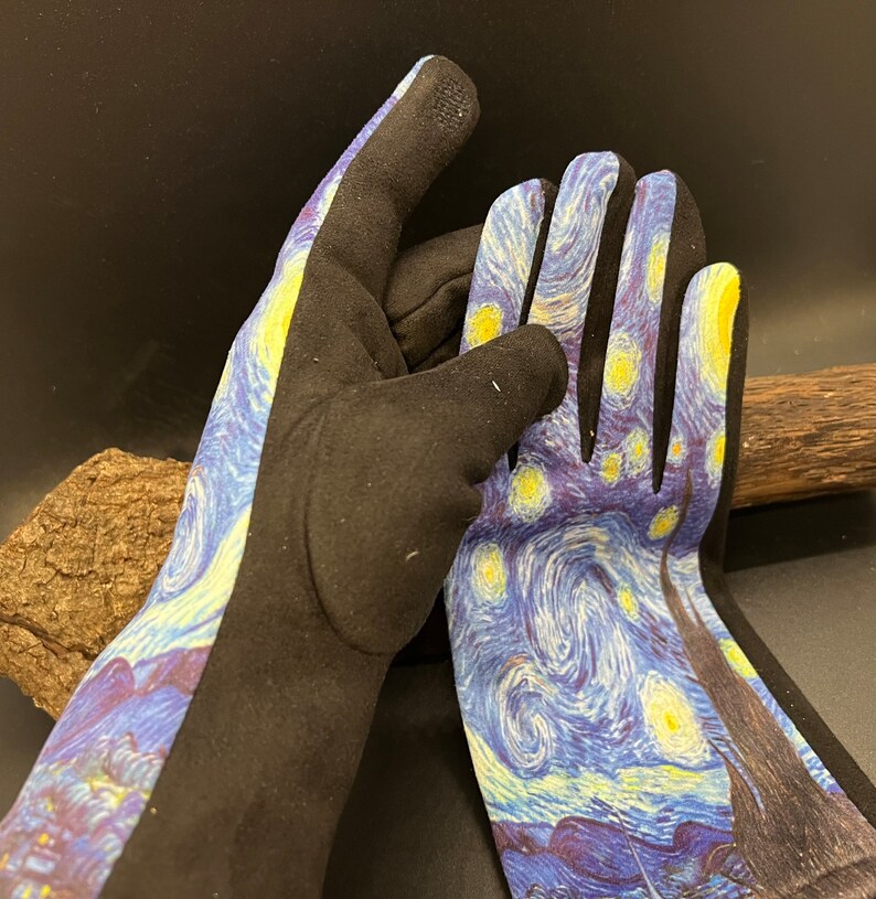 May include: A pair of gardening gloves featuring a print of Van Gogh's "Starry Night" painting. The gloves have a black palm and fingers, with the artwork covering the back of the hand and wrist area. The artwork includes yellow stars and a blue night sky.