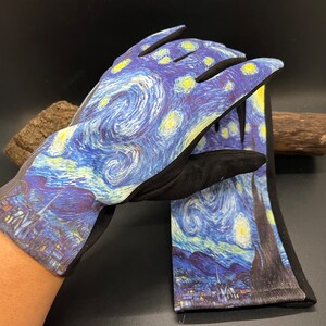 May include: A pair of gloves featuring a print of Van Gogh's "Starry Night" painting. The gloves have a black cuff and palm, with the iconic swirling blue, yellow, and white design covering the top of the hand and fingers. The gloves are likely for gardening or general use.