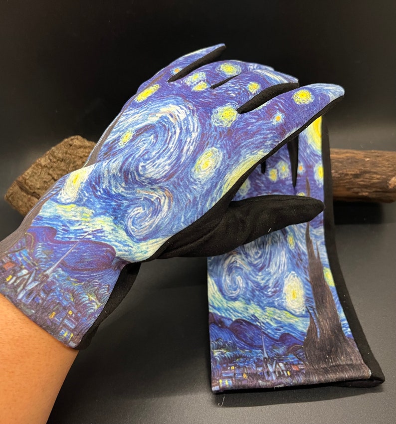 May include: A pair of gloves featuring a print of Van Gogh's "Starry Night" painting. The gloves have a black cuff and palm, with the iconic swirling blue, yellow, and white design covering the top of the hand and fingers. The gloves are likely for gardening or general use.