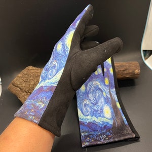 May include: A pair of black gloves with a print of Van Gogh's "Starry Night" painting. The gloves feature a black cuff and a black side panel. The artwork depicts a swirling blue night sky with yellow stars and a village.