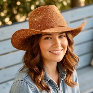 May include: A brown straw cowboy hat with a wide brim and a brown leather band. The hat is made of woven straw material and has a classic western style. The hat is designed to provide shade from the sun.