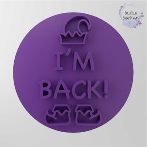 May include: Purple round cookie cutter with the text "I'M BACK!" and a hat and shoes on top and bottom.