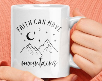 May include: White ceramic mug with a black and white design. The design features a crescent moon, stars, and mountains. The text "Faith can move mountains" is printed on the mug.