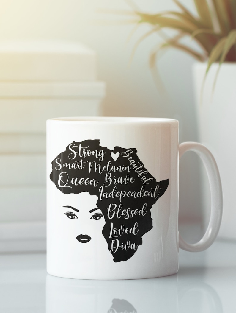 Pode incluir: Caneca de cer&acirc;mica branca com uma silhueta preta do continente africano. O continente est&aacute; cheio de texto que diz "Strong, Smart, Melanin, Queen, Brave, Independent, Blessed, Loved, Diva". Um s&iacute;mbolo de cora&ccedil;&atilde;o est&aacute; entre "Strong" e "Beautiful". Uma ilustra&ccedil;&atilde;o em preto e branco do rosto de uma mulher est&aacute; no centro do continente.