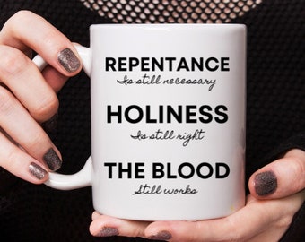 Peut inclure: Une tasse en céramique blanche avec du texte noir qui dit "Repentance is still necessary, Holiness is still right, The Blood still works."