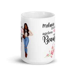 May include: White ceramic mug with a black and white illustration of a woman with brown hair and a pink floral design. The text "melanin infused ageless beauty" is printed on the mug.