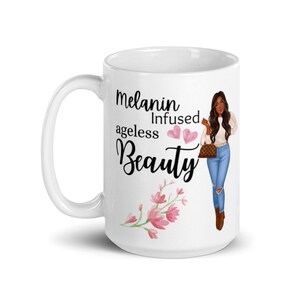 May include: White ceramic mug with a black and white graphic of a woman with brown hair and a white shirt and blue jeans. The text on the mug reads "Melanin Infused ageless Beauty" with two pink hearts.