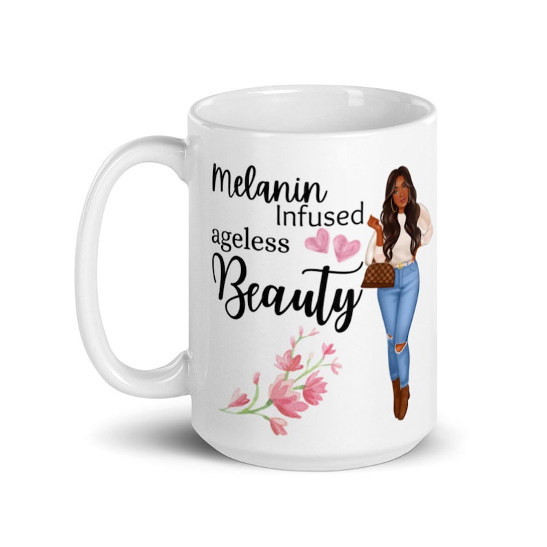 May include: White ceramic mug with a black and white graphic of a woman with brown hair and a white shirt and blue jeans. The text on the mug reads "Melanin Infused ageless Beauty" with two pink hearts.