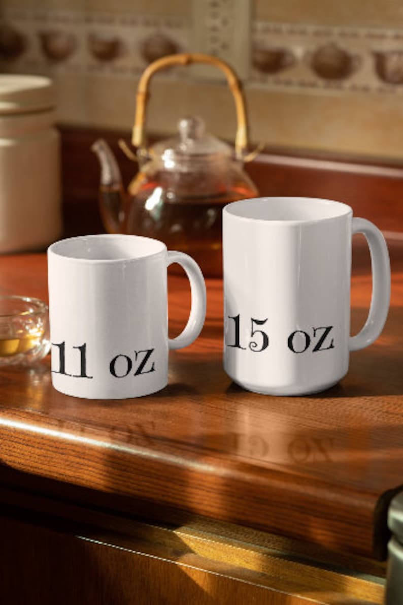 May include: Two white ceramic mugs with black text. The smaller mug says "11 oz" and the larger mug says "15 oz".