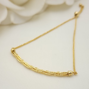 May include: A gold chain bracelet with a braided design and adjustable sliding clasp.