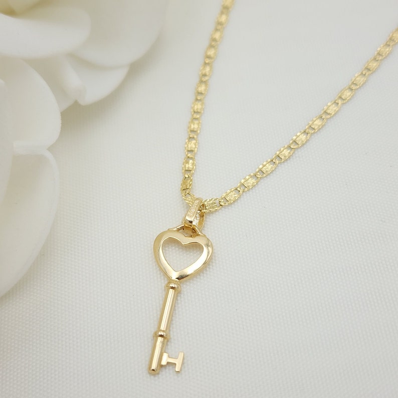 May include: A gold heart-shaped key pendant necklace with a delicate chain. The key has a smooth, rounded design and a small loop at the top for attaching to the chain.