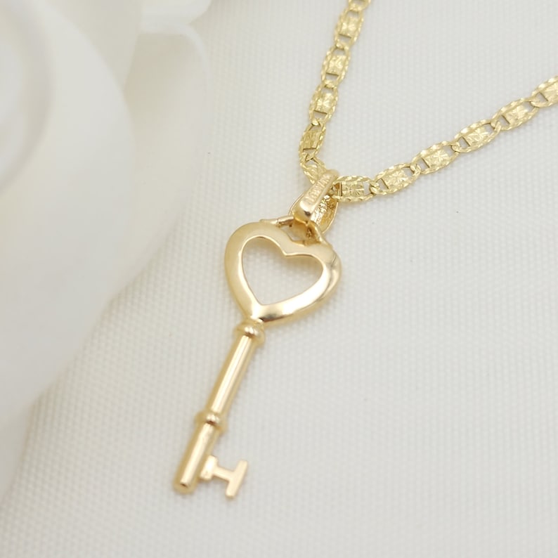 May include: A gold heart-shaped key pendant necklace with a delicate chain. The key has a small loop at the top for attaching to the chain.