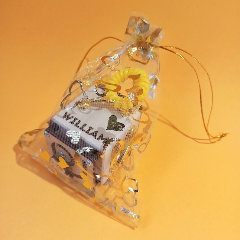May include: A small wooden box with the name "William" engraved on it, inside a sheer gold and white heart-shaped bag with a yellow heart-shaped ribbon.