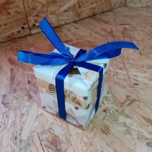 May include: A small gift box wrapped in white paper with a seashell pattern and tied with a blue ribbon.