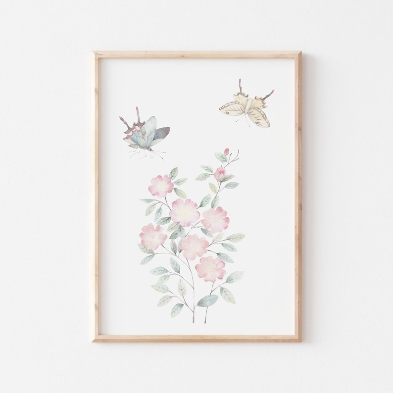 Op de afbeelding: Ingelijste aquarelprint van roze bloemen en vlinders. Het kunstwerk toont twee vlinders en een bloemstuk met lichtroze bloesems en groene bladeren. De vlinders hebben blauwe en beige vleugels.