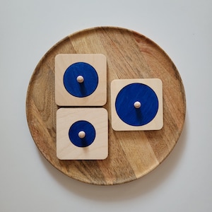 Peut inclure: Trois pièces de puzzle en bois avec des cercles bleus au centre. Les pièces sont sur un plateau en bois.