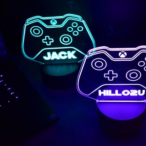 May include: Two illuminated gamer controller night lights, one blue and one purple, with the names "JACK" and "HILLOZU" printed on them.