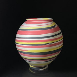 May include: A round ceramic vase with a wide opening and a small base. The vase is decorated with horizontal stripes in shades of red, white, yellow, and gray. The stripes have a brushstroke effect, adding texture to the design.