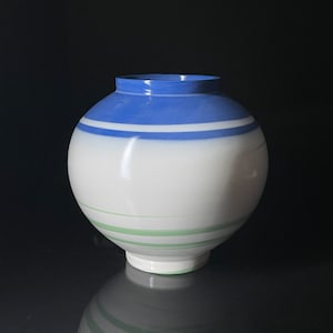 Könnte beinhalten: Eine weiße Keramikvase mit blauen und grünen Streifen. Die Vase hat einen runden Körper und einen kleinen Boden.