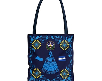 May include: Navy blue tote bag featuring a design with the El Salvador coat of arms, a woman in a dress, the El Salvador flag, and the words "El Salvador" in a circular pattern. The bag has a floral border with yellow and blue flowers.