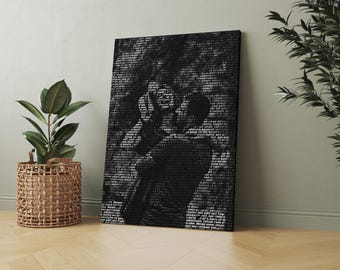 May include: A black and white canvas print depicting a couple embracing, made up of text. The artwork is propped against a pale green wall, beside a potted plant in a woven basket. The floor is light brown.