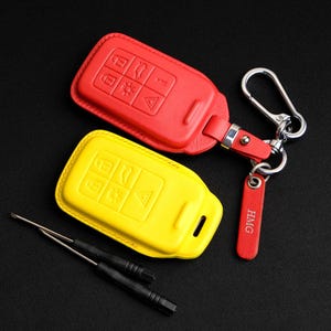May include: Two key fobs, one red and one yellow, with a silver key chain and a red leather tag that says "HMG".