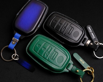 May include: Three leather key covers in blue, black, and green. Each cover has a different design and features a metal ring and a small tag with the words "Zoom-Zoom" and "SCRA" on them.