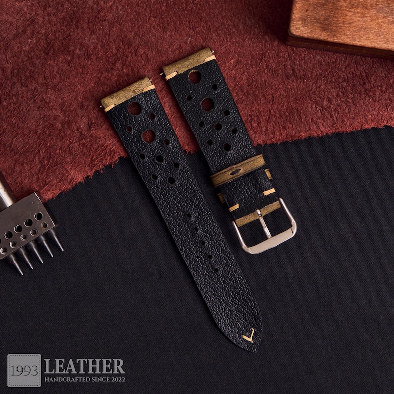 Puede incluir: Correas de reloj de cuero negro con herrajes de metal color lat&oacute;n. Las correas tienen un dise&ntilde;o perforado y una hebilla plateada. La imagen tambi&eacute;n muestra una herramienta de artesan&iacute;a en cuero y el texto "1993 LEATHER HANDCRAFTED SINCE 2022".