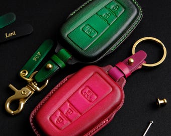 May include: Two leather key covers with key rings. One is green and the other is pink. Both have three buttons and the text "HOLD" and "LOCK" on them.