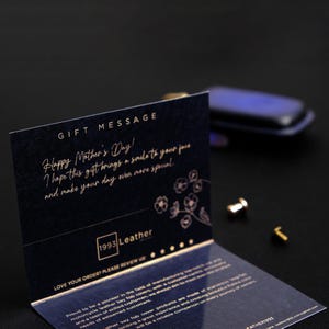 May include: A black card with gold lettering that says "Gift Message" and "Happy Mother's Day! I hope this gift brings a smile to your face and make your day even more special." The card also has a floral design and the logo "1993 Leather".