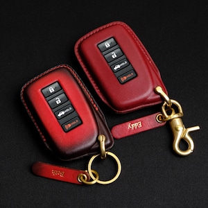 May include: Two red leather key fobs with gold key rings and personalised tags that read "Eddy" and "Beth".