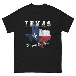 Op de afbeelding: Zwart T-shirt met een verweerde witte afbeelding van de staat Texas met de vlag van Texas en de tekst "TEXAS The Lone Star State".
