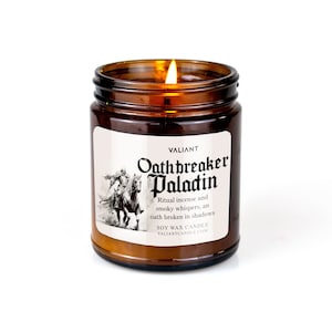 Peut inclure: Un bocal en verre brun contenant une bougie avec une étiquette blanche. L'étiquette comporte du texte noir qui dit "VALIANT Oathbreaker Paladin Ritual incense and smoky whispers, an oath broken in shadows SOY WAX CANDLE VALIANTCANDLE.COM".
