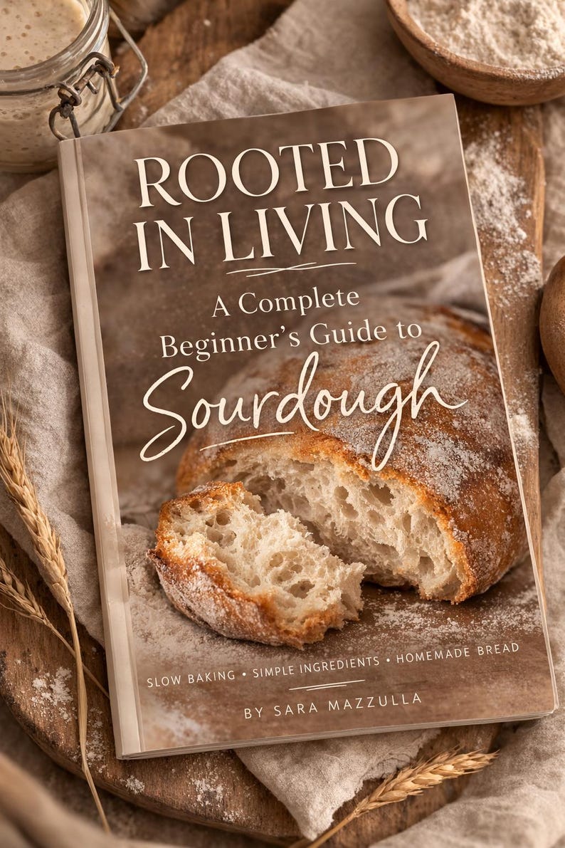 May include: A cookbook titled "ROOTED IN LIVING" with the subtitle "A Complete Beginner's Guide to Sourdough" is displayed open, revealing a sliced loaf of bread. The book cover is light brown with white text. The image includes wheat stalks and a jar.
