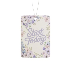Può includere: Deodorante per ambienti rettangolare con un design floreale nei toni del viola, blu e rosa. Le parole "Start Today" sono scritte in corsivo al centro. Un cordino bianco è attaccato in alto.