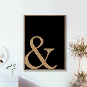 May include: A black and white framed print with a large gold ampersand symbol on a black background.